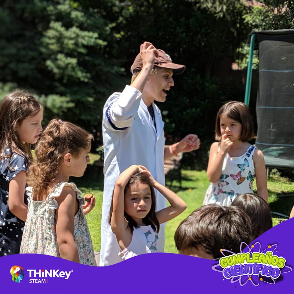 "Man in white coat explaining something to children in park."
